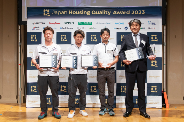 受賞式の様子 建物部門 Japan Housing Quality Award 2023のパネルの前に並ぶ受賞者の方々